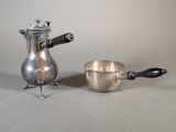 a silver coffee pot and a silver cup on a table