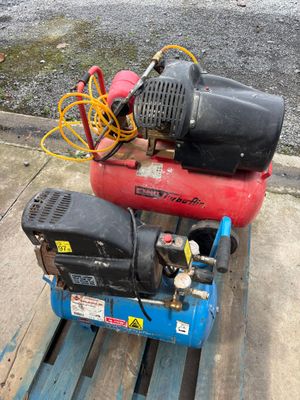 two air compressors sitting on a pallet on the sidewalk