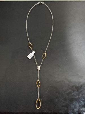 un collier en argent et en or sur un fond noir, orné d'une médaille