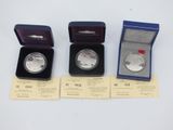 three silver coins are in a blue box on a white surface
