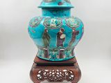 un vase bleu muni d'un couvercle, posé sur un socle
