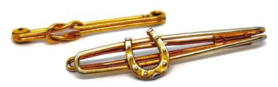 une paire de barrettes de couleur dorée avec un fermoir en forme de fer à cheval