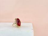 une bague en pierre rouge posée sur un bloc de marbre blanc
