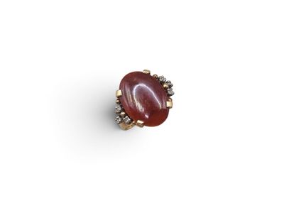 a close up of a red stone ring on a white surface