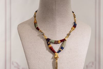 collier de perles orné d'un pompon, posé sur le cou d'un mannequin