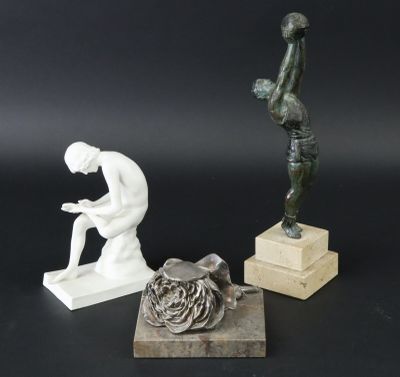 trois sculptures représentant un homme assis sur un bloc de bois