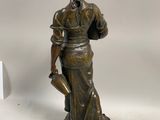 statue en bronze représentant une femme tenant un arrosoir, posée sur un socle en bois