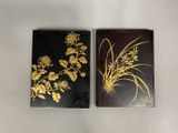 two black and gold coasters with flowers on them on a white surface