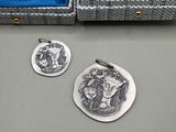 deux pièces d'argent dans un étui bleu posé sur une table, à côté d'une pièce d'argent