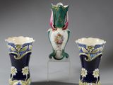 trois vases sont posés sur un socle, sur une surface grise