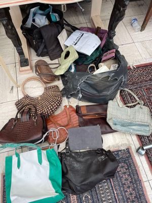 a pile of purses on the floor next to a table