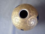 a gold and blue vase sitting on a table