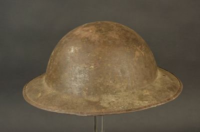 un vieux casque posé sur un support métallique, sur fond gris