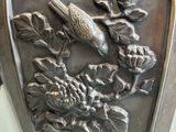 a silver vase with a bird and flowers on it