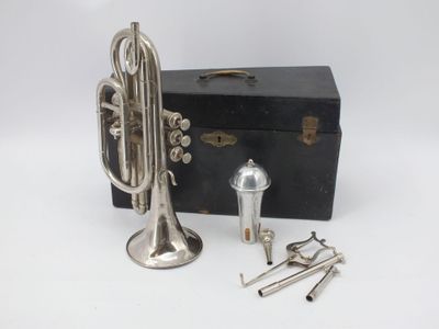 an antique silver plated trumpet and other musical instruments on a white surface