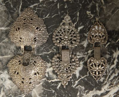 several antique silver jewelry pieces on a marble surface