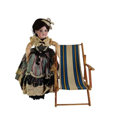 une poupée assise sur une chaise, à côté d'une chaise longue