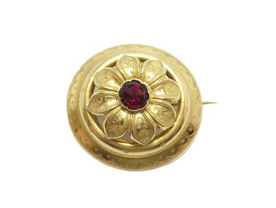 gros plan d'une bague en or avec une pierre rouge au centre
