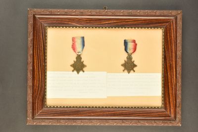 an old picture of two medals on display in a wooden frame