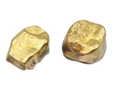 deux pépites d'or posées l'une à côté de l'autre sur une surface blanche