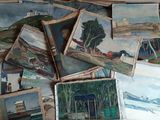 une pile de tableaux posés par terre dans une pièce