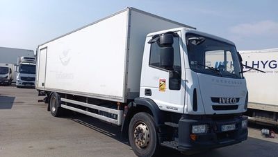 a white truck parked in a parking lot with other trucks in the background