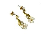 une paire de boucles d'oreilles en perles et or sur fond blanc
