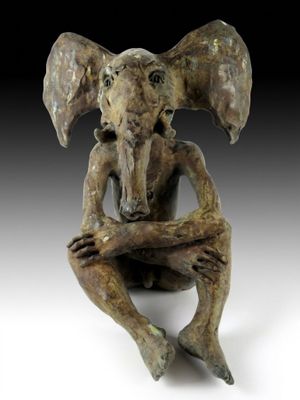 statue d'un éléphant assis par terre, la tête posée sur ses pattes avant