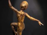 a bronze statue of a woman holding a ball on top of a wooden base