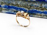 un gros plan d'une bague en or avec une pierre en arrière-plan