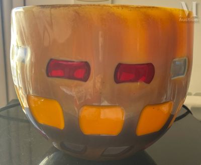 un bol en verre orné d'un visage, posé sur une table