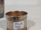 une coupe en argent sur laquelle est collé un autocollant, à côté d'une autre coupe en argent sur laquelle est collé un autocollant