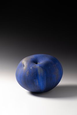 une pomme bleue posée sur une surface blanche