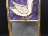 un oiseau violet et doré sur un miroir, sur fond noir