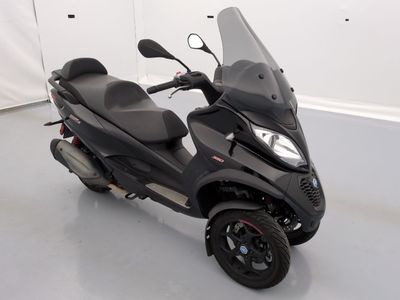 un scooter noir garé dans une pièce aux murs blancs