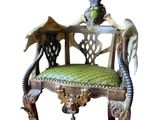 une chaise en bois avec une assise rembourrée verte sur laquelle est posé un oiseau