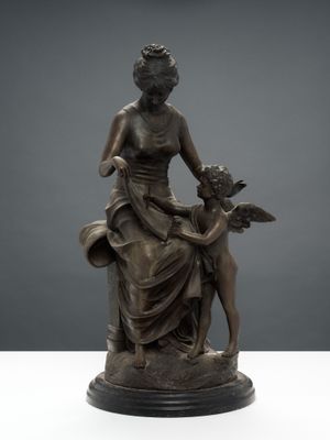 une statue en bronze représentant une femme tenant un enfant et un chien dans ses bras