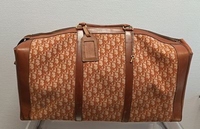 un sac de voyage marron et blanc posé sur une chaise