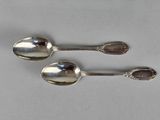 pair of silver spoons sitting on top of a white surface
