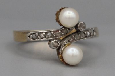 une photo d'une bague en perle et diamant posée sur une surface grise