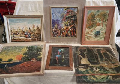de nombreux tableaux exposés sur une table recouverte d'une nappe blanche