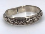 a close up of a silver bracelet on a white surface