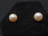 a pair of pearl earrings on a black surface
