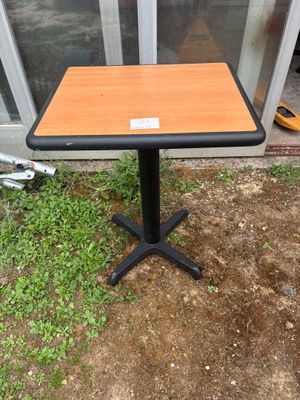 une petite table en bois posée à même le sol, avec un piètement noir
