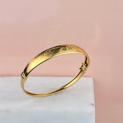 a close up of a gold bang bracelet on a marble surface