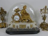 une horloge en or sous un dôme de verre sur une table