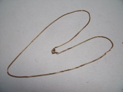 a close up of a gold chain on a white surface