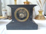 a black clock sitting on a table next to a gold lamp