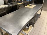 plan de travail en acier inoxydable dans une cuisine commerciale avec des casseroles et des poêles dessus