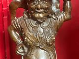 bronze statue of a man holding a large bowl on his head